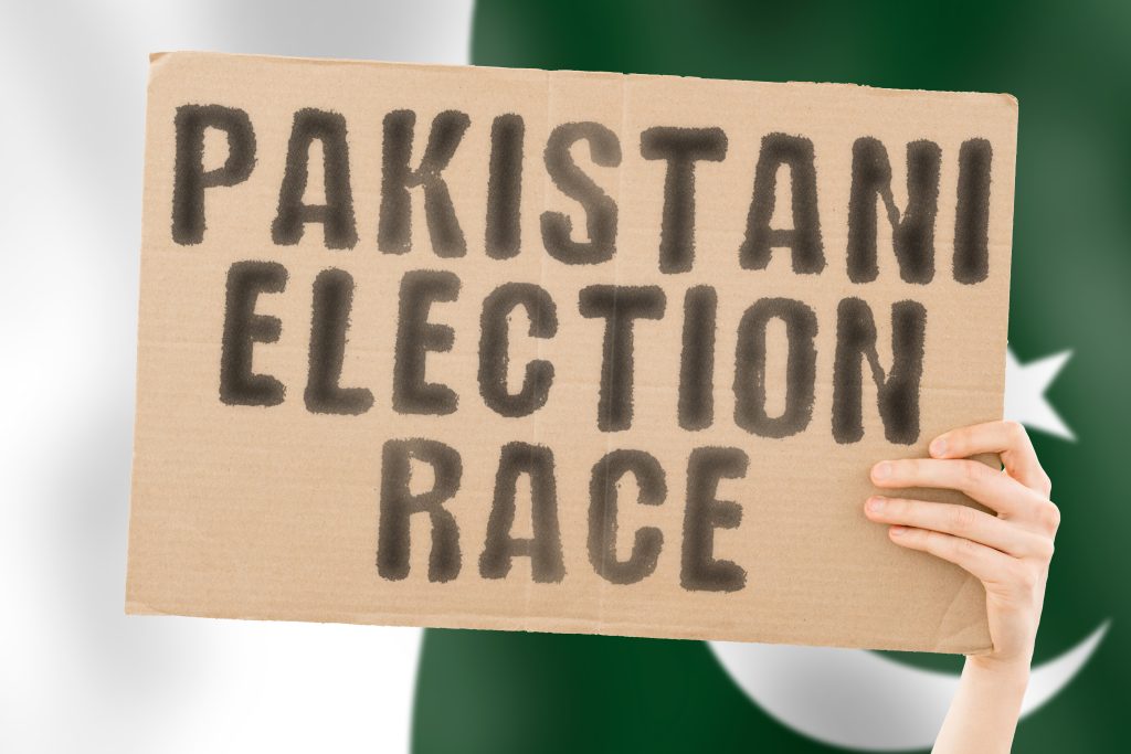This image has an empty alt attribute; its file name is phrase-pakistani-election-race-banner-men-s-hand-with-blurred-pakistani-flag-background-ballot-box-politics-conflict-politic-primary-selection-choosing-karachi-1024x683.jpeg